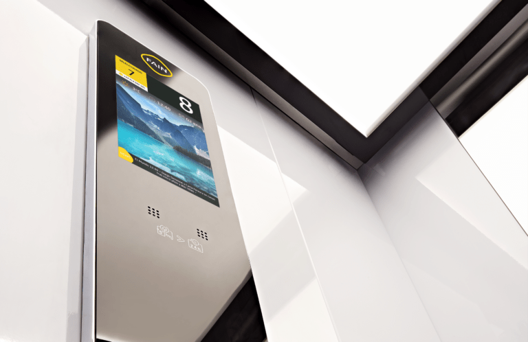 Image d'une main appuyant sur le bouton 'L' éclairé du panneau de contrôle d'un ascenseur, entouré des boutons des étages et de commandes d'ouverture et de fermeture des portes.