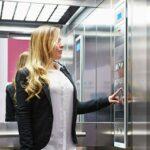 Une femme dans un ascenseur est en train d'appuyer sur un bouton.
