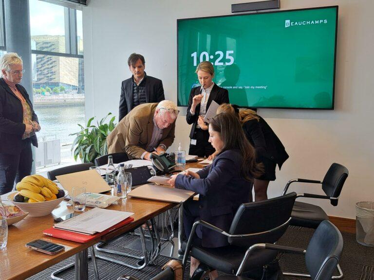 Six personnes dans une salle de réunion avec vue sur une rivière, réunies pour une collaboration entre FAIN et Doyle Lift Services.