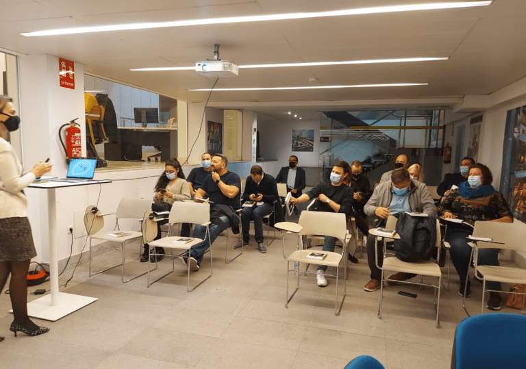 Groupe de personnes assistant à une session de formation dans une salle équipée d’un projecteur.