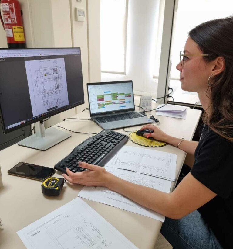 Maria souriante en veste noire portant le logo FAIN 3, sur fond clair.