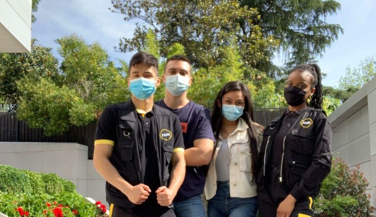 Personne assise devant un bureau dans un environnement professionnel, avec logo et panneaux de sécurité visibles.