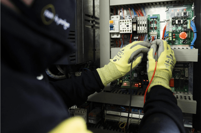 Deux techniciens FAIN en tenue de travail manipulant des outils dans un environnement intérieur.